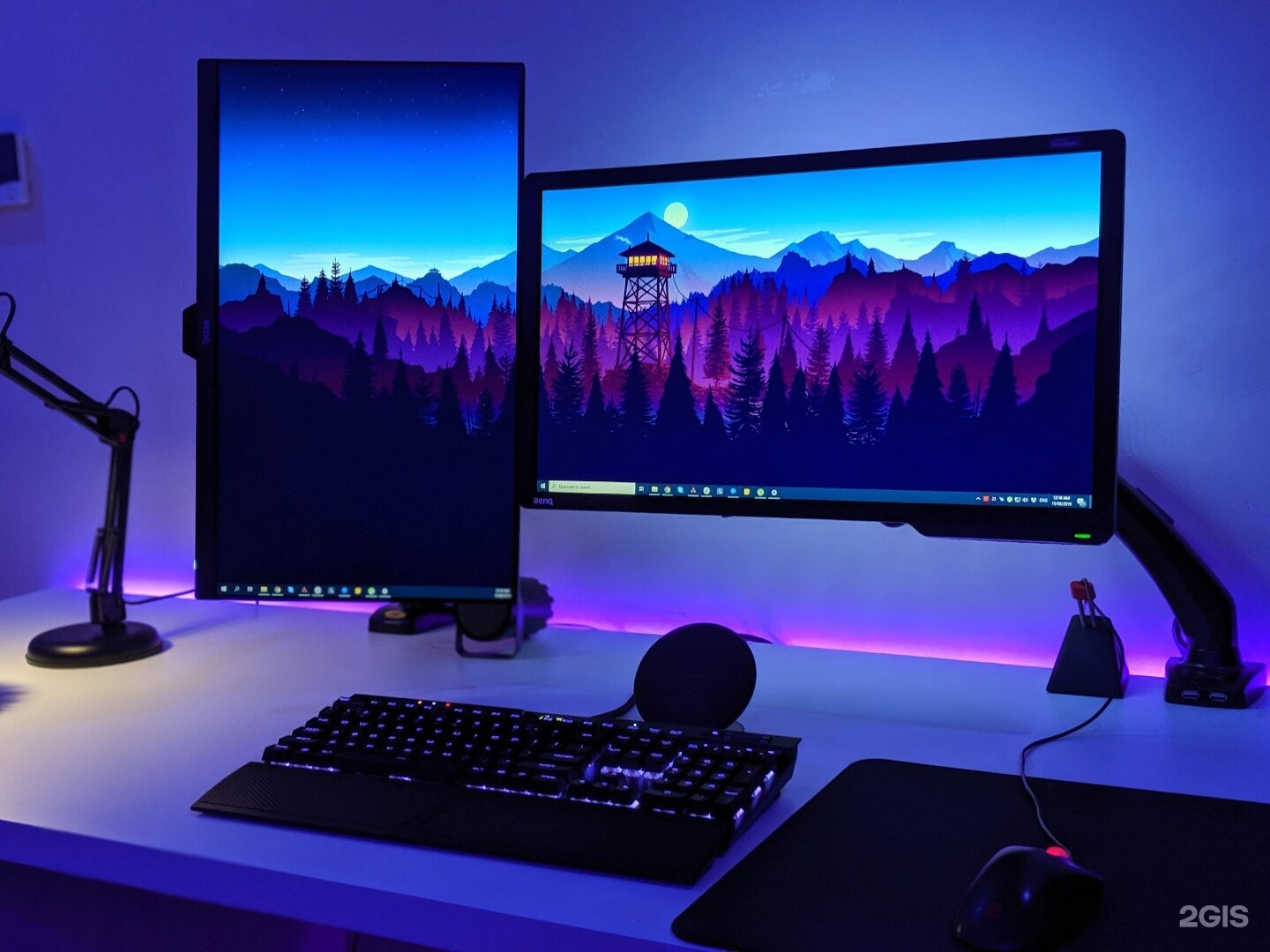 A high-end modern gaming setup with ergonomic chair, dual monitors, and ambient LED lighting
